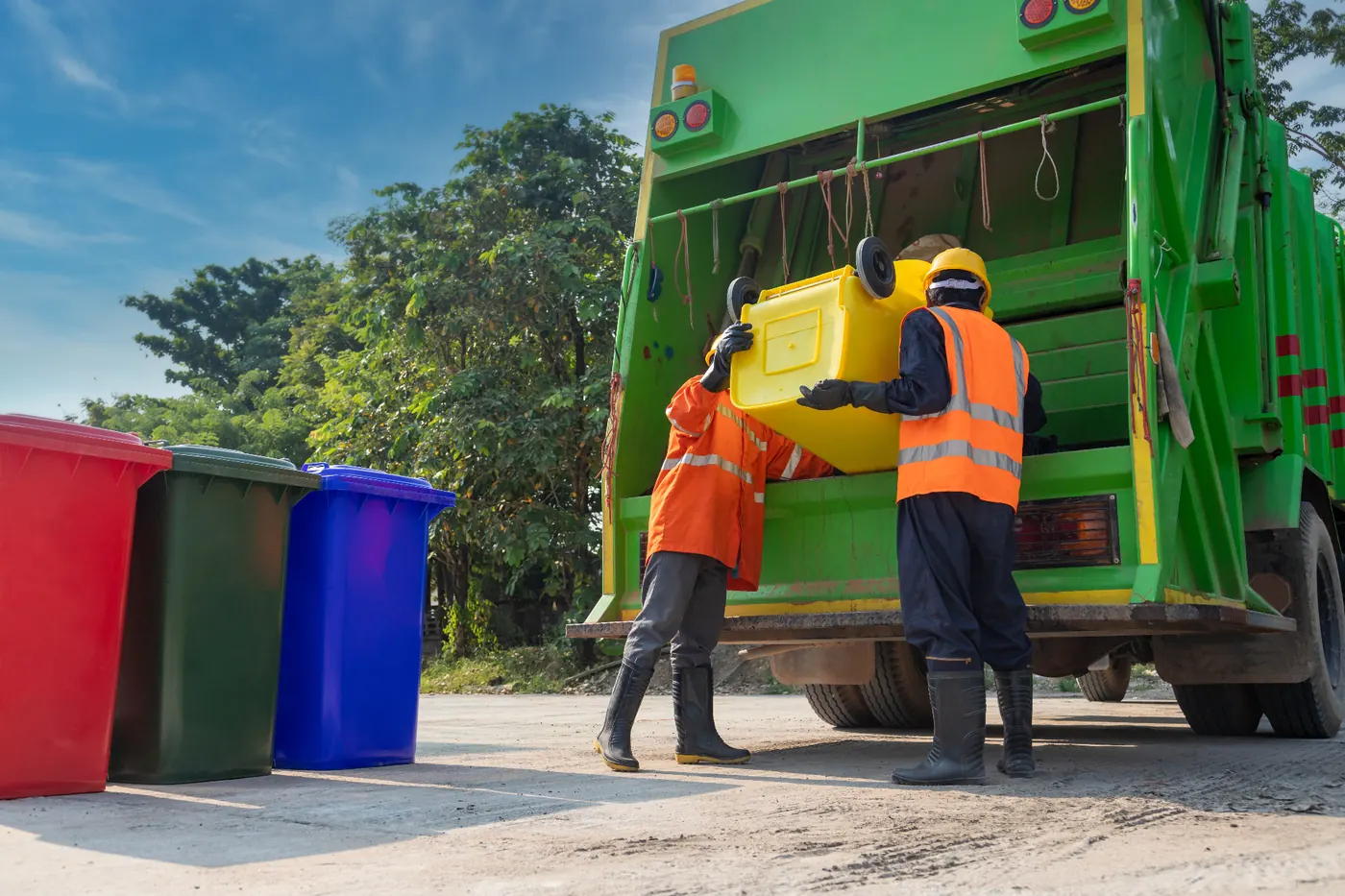 Equipo de recolección de residuos cargando contenedor en unidad verde